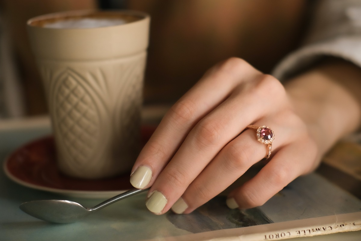 kubek z kawa i dłoń damska z pierścionkiem z rubinem